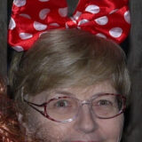 Headshot of the author wearing red and white polka dot Mini Mouse bow in her hair.